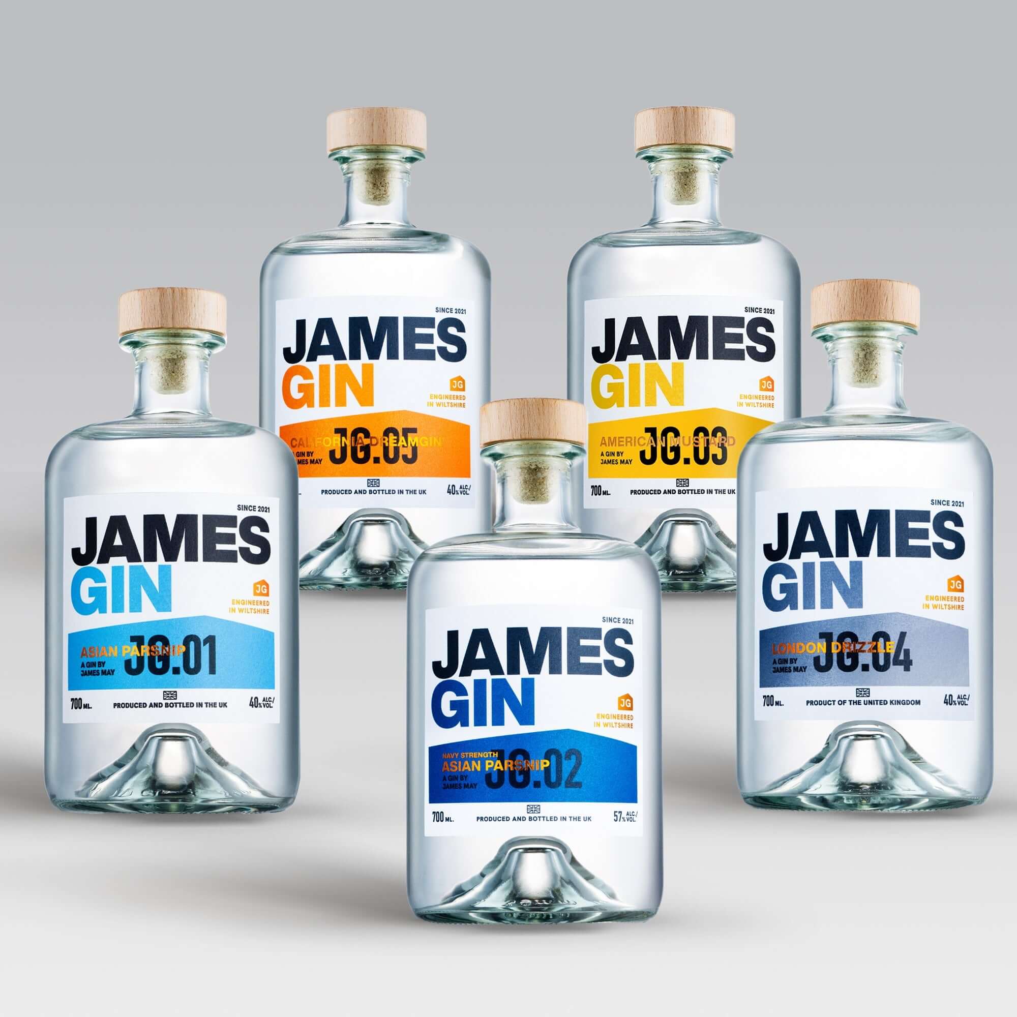 The James Gin US "The Famous Five" 5 Bottle Bundle with souvenir gift key chain is displayed against a gradient gray backdrop, each bottle featuring bold text and colored accents—a perfect craft gin collection for enthusiasts.