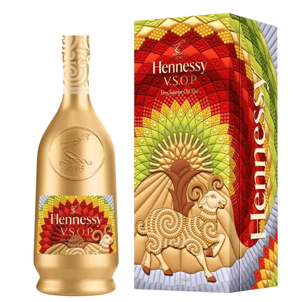 A gold Hennessy V.S.O.P Year Of The Goat Limited Edition by Raxxy (Pre-Order) bottle stands beside a colorful box adorned with a ram and a vibrant, patterned background in red, yellow, and green, featuring the Hennessy logo to celebrate this exclusive cognac.