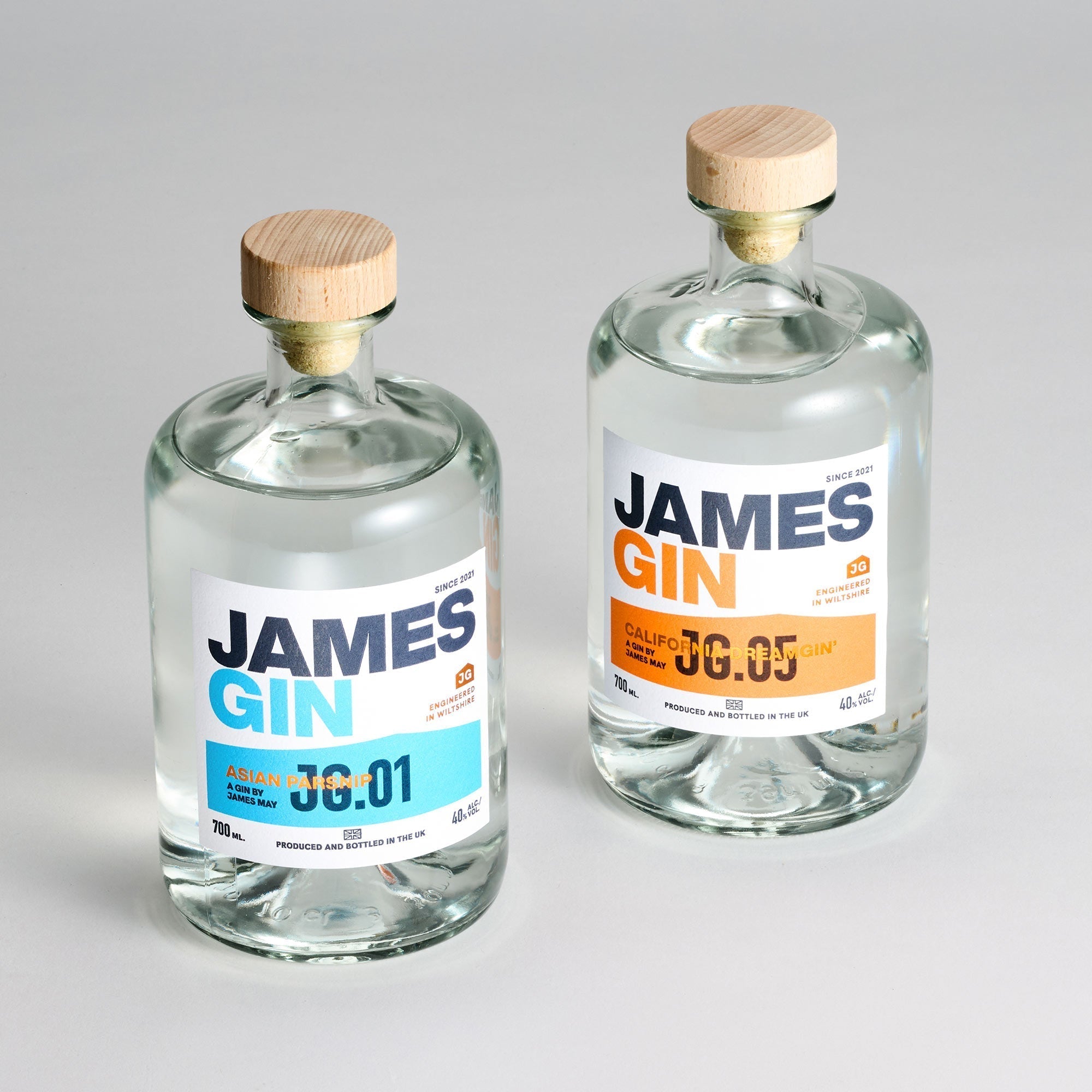 Two clear James Gin US bottles—The Internationalist 700ml editions (Asian Parsnip 73:01 and California 08:05)—come with a wooden cap, blue and orange accents, plus a souvenir gift key chain. Ideal for gin enthusiasts.