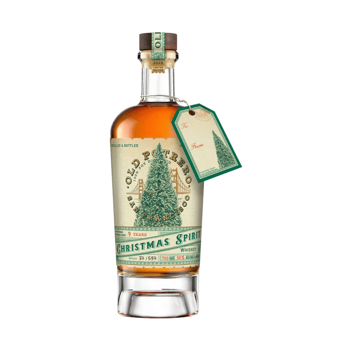 A 700mL bottle of Old Potrero 2025 Christmas Spirit Whiskey 9 Year Limited Edition, featuring a festive label with a decorated Christmas tree and a green and gold gift tag attached to the neck.