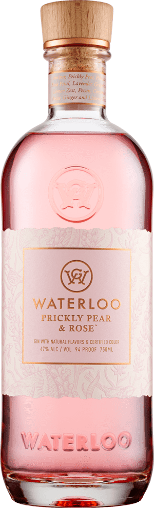 A clear glass bottle of Waterloo Prickly Pear & Rose Gin by Waterloo Gin features pale pink liquid, a wooden cap, and a light pink label with gold accents and text. WATERLOO is embossed on the bottom.
