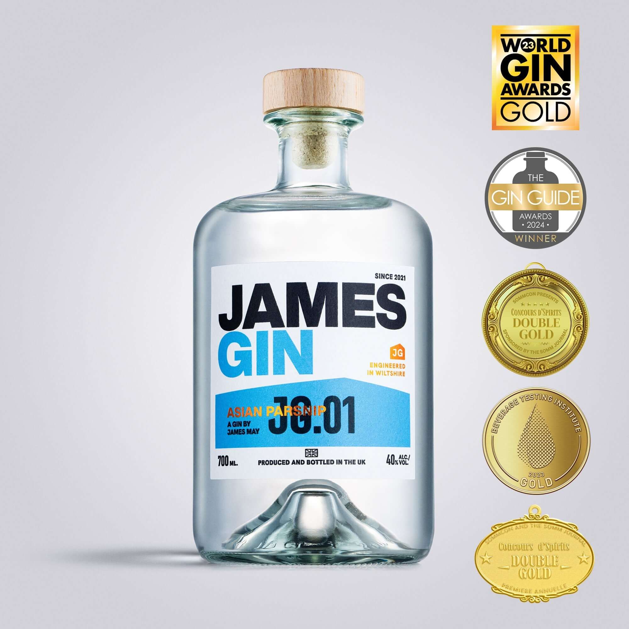 A clear 700mL bottle of James Gin Asian Parsnip 80 Proof with wooden cap and a souvenir gift key chain is shown alongside four gold award medals—showcasing this premium British gin’s award-winning quality.