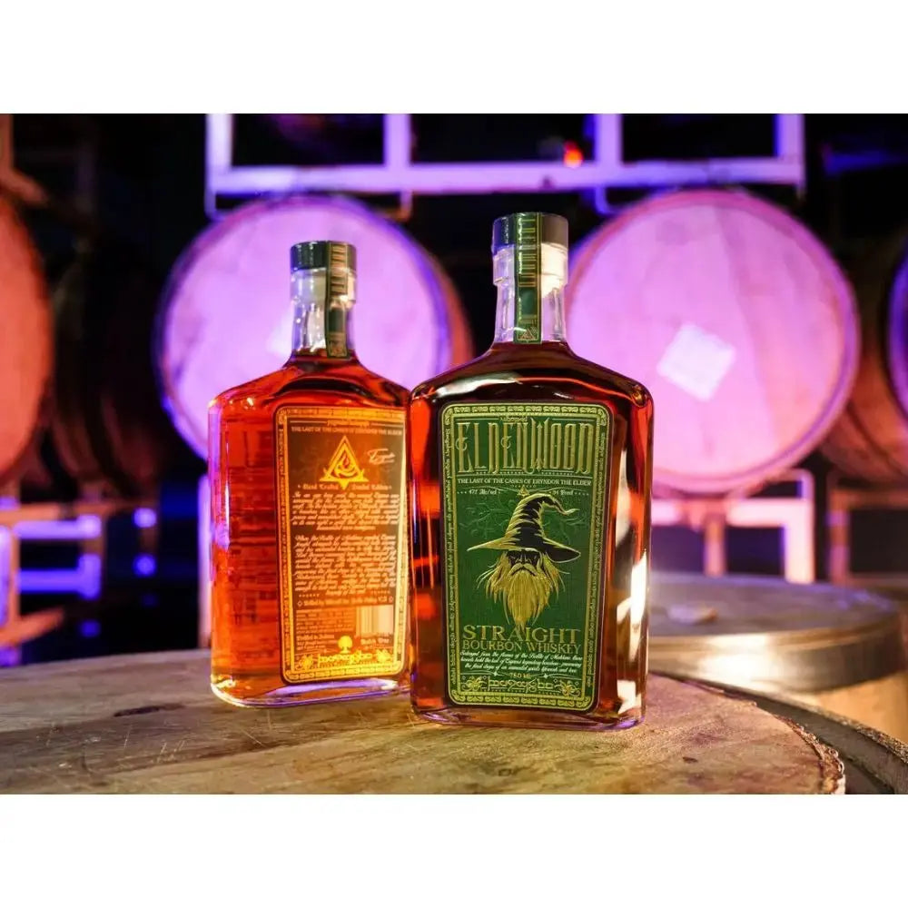 Two bottles of Eldenwood Straight Bourbon Whiskey with Drinking Horn from Eldenwood are displayed atop a wooden barrel, highlighting both the front and back labels. In the softly blurred background, large wooden barrels glow under purple lighting, creating a striking atmosphere ideal for showcasing this refined bourbon gift set.