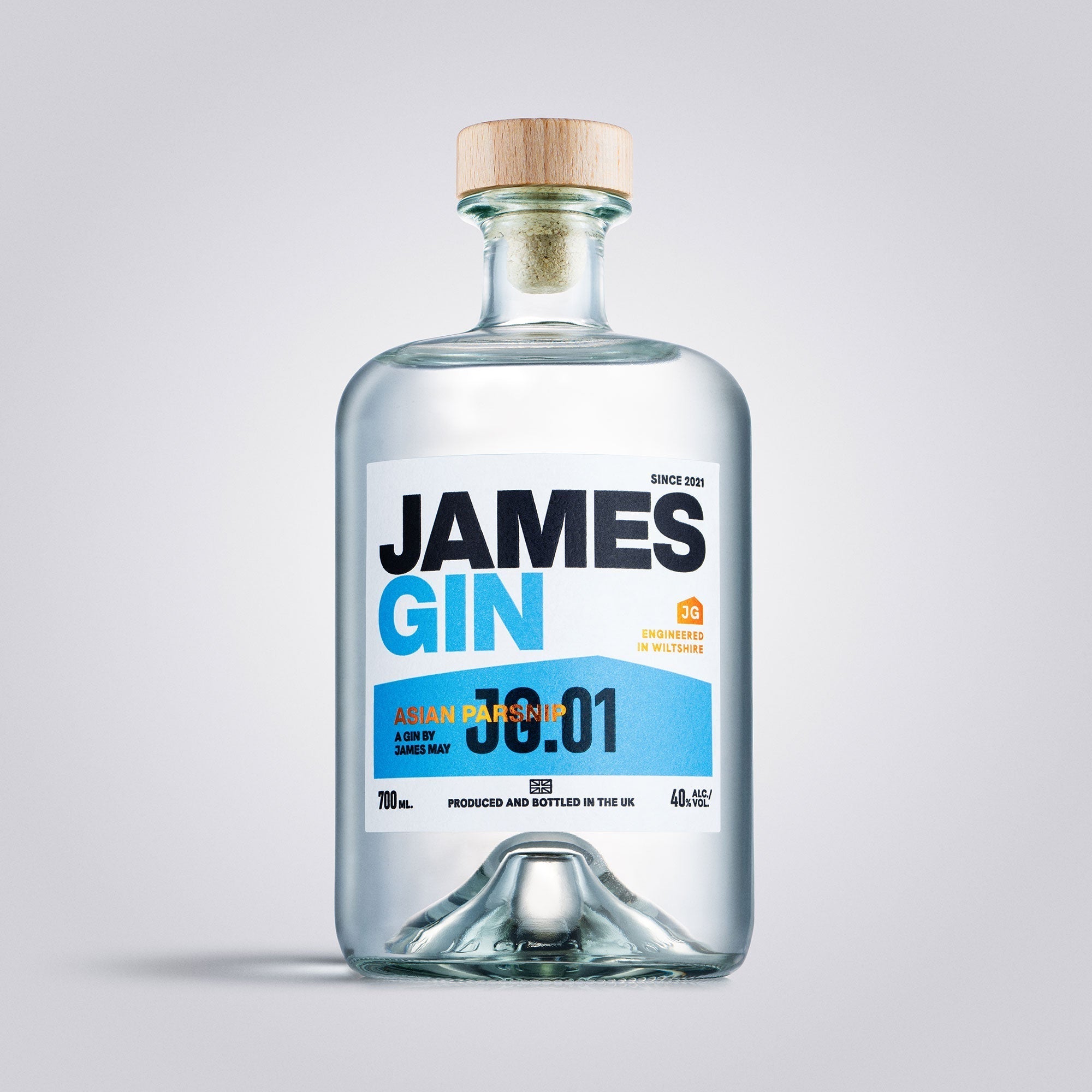 A clear glass 700mL bottle of James Gin Asian Parsnip (80 Proof) with a wooden cap and blue-and-white label is photographed on a light gray background, highlighting the premium British gin and its souvenir gift key chain.