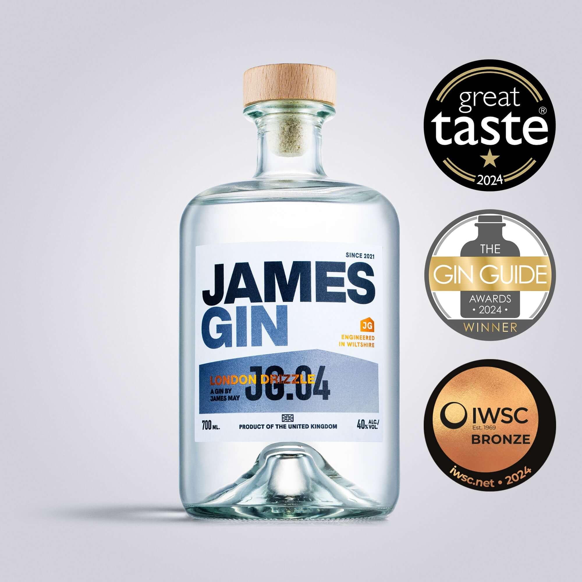 A 700mL bottle of James Gin London Drizzle (80 Proof) with a gift key chain is shown with bold blue and orange labeling, wooden cap, and award badges: Great Taste 2024, Gin Guide Awards Winner 2024, IWSC Bronze 2024.