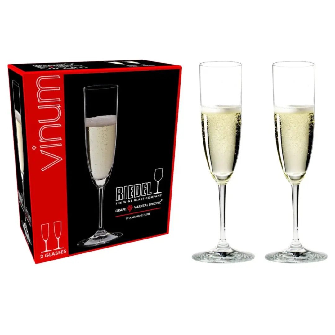 A black box labeled "RIEDEL Flute Vinum Champagne Set of 2" by Riedel is shown next to two filled champagne flutes. The box features red accents and displays “2 glasses” along with an image of a flute. These elegant crystal Champagne flutes are perfect for celebrating special occasions and enhancing your sparkling wine experience.